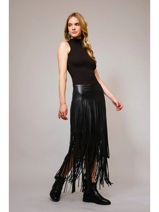 Full-length view of a model wearing a black faux leather tiered fringe maxi skirt with black boots.